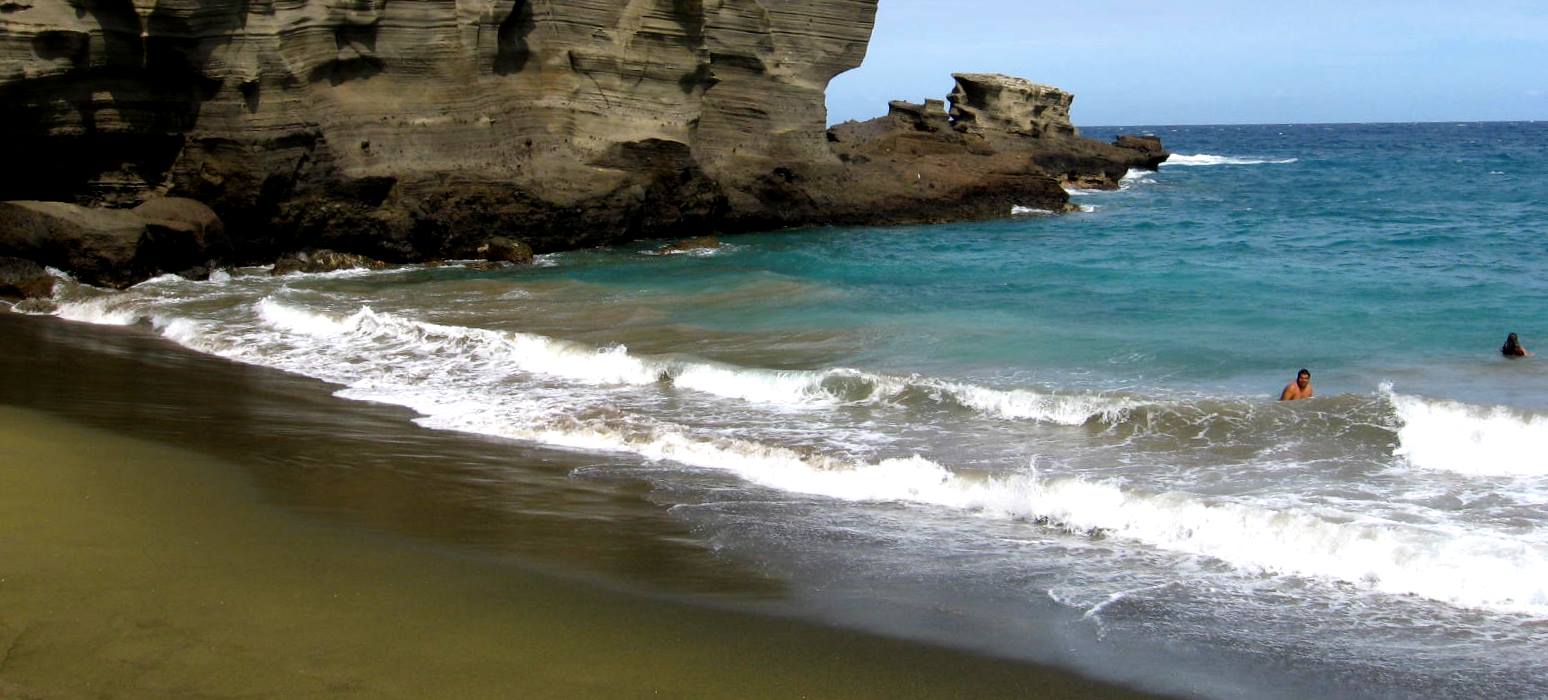 Figure 17.5 Waves breaking on the shore at Greensand Beach, Hawaii (the sand is green because it is made up mostly of the mineral olivine eroded from the nearby volcanic rocks) [SE]