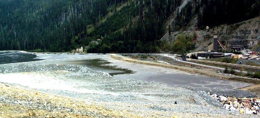 Figure 20.12 The tailings pond at the Myra Falls Mine on Vancouver Island. The dry rock in the middle of the image is waste rock. The structure on the right is the headframe for the mine shaft. Myra Creek flows between the tailings pond and the headframe. [SE]