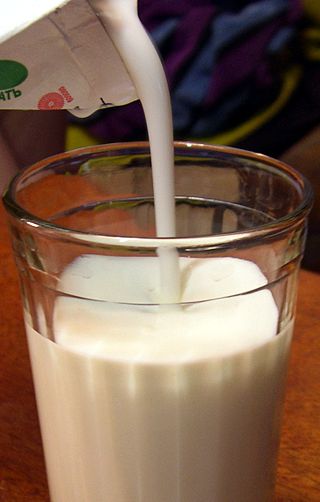 A glass with Kefir being poured into it.