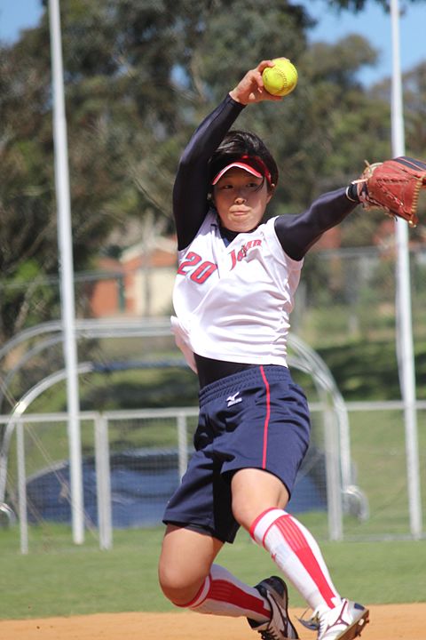 A woman's fast pitch softball pitcher winds up to deliver a pitch.