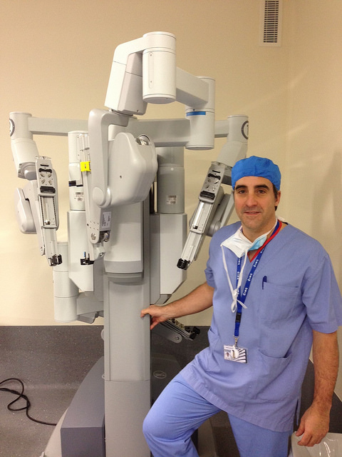 A surgeon next to the Da Vinci Robot, a machine with multiple arms made for surgery