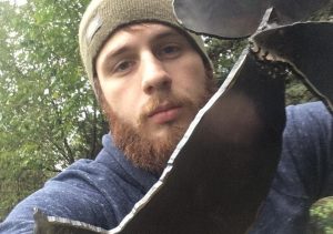 Young man standing behind a metal sculpture