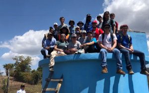 Group of young adults sitting on top of a blue platform.