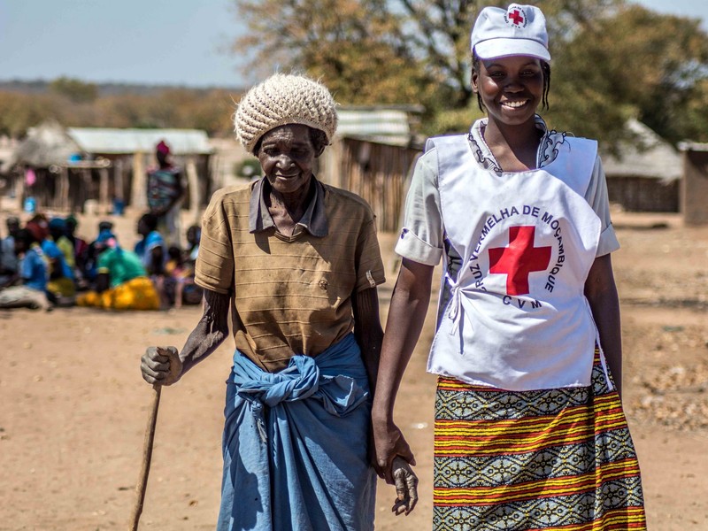 A Red Cross volunteer assists an elderly lady from Mozambique, where a food distribution was taking place.