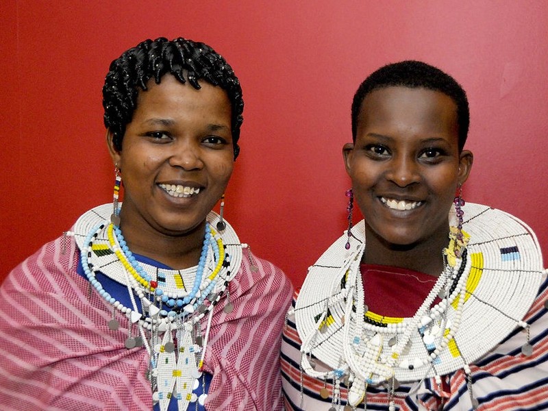 Two teen aged Maasai girls pose together in traditional clothing.
