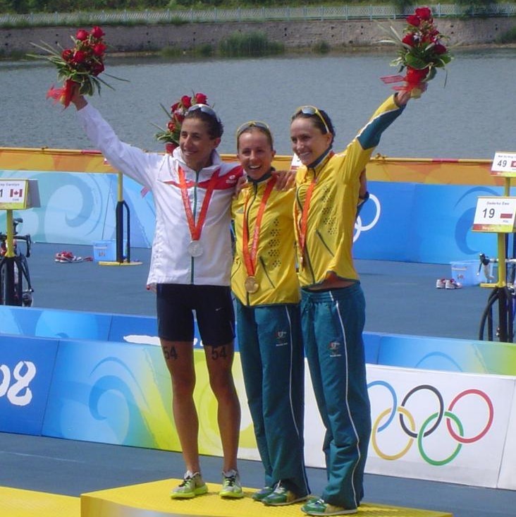 The three medalists in the 2008 Women's Olympic Triathlon stand together on the winner's podium.