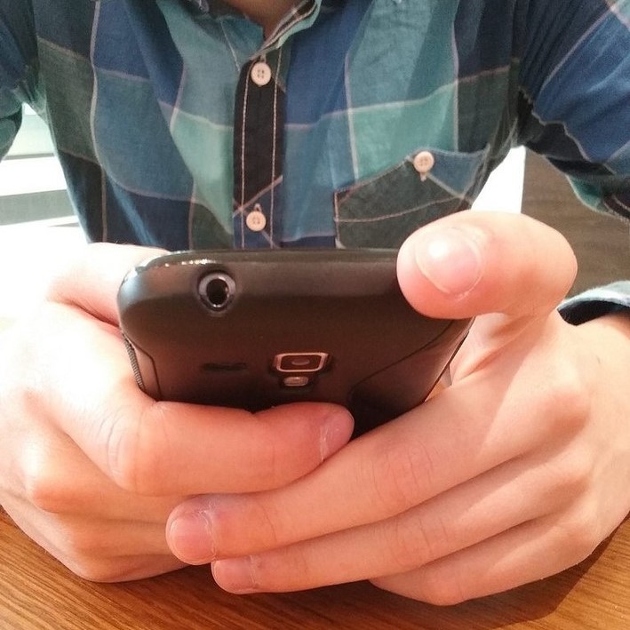 Person seated at a desk using a smartphone.