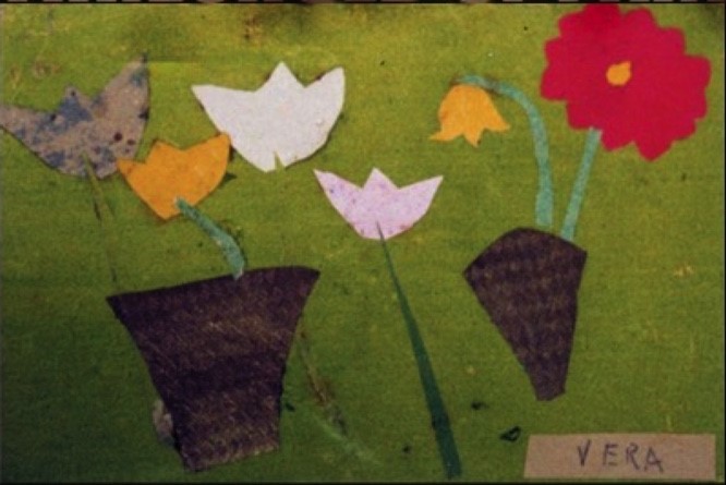 A drawing shows two rudimentary baskets with flowers in them on a green background. In the lower right is the word "Vera".