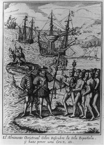 Christopher Columbus being greeted by indigenous people upon his landing on the island of Hispaniola. In the background, soldiers plant a cross and indigenous women flee from the arriving sailors.