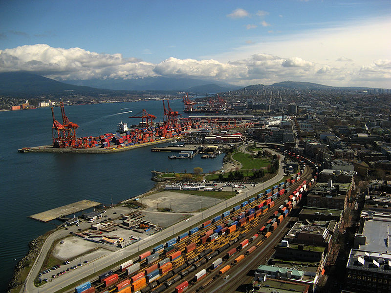 Port of Vancouver. Many cranes and shipping containers along edges of the port.
