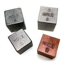 Picture of 4 blocks of metal that are 1 cubic inch. One is reddish while the others are variations of gray and silver.