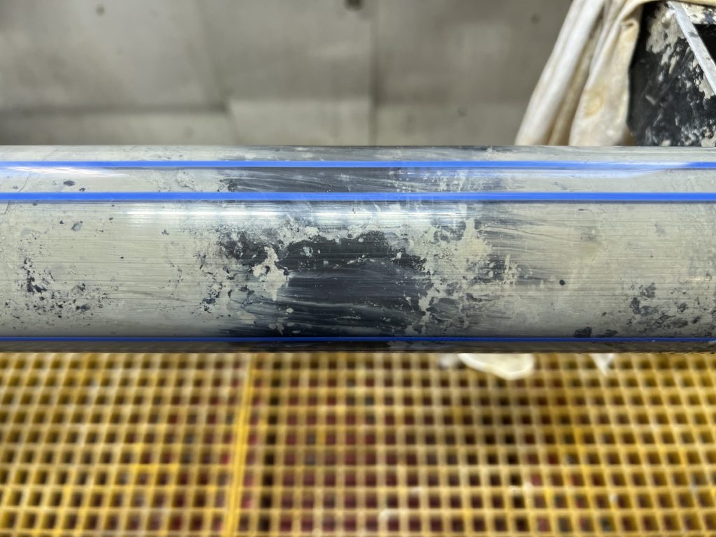 a transparent tube with grey and black mud inside it.