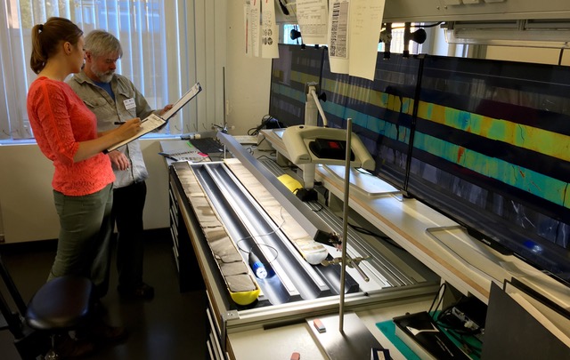 Two people looking at a split core on a table