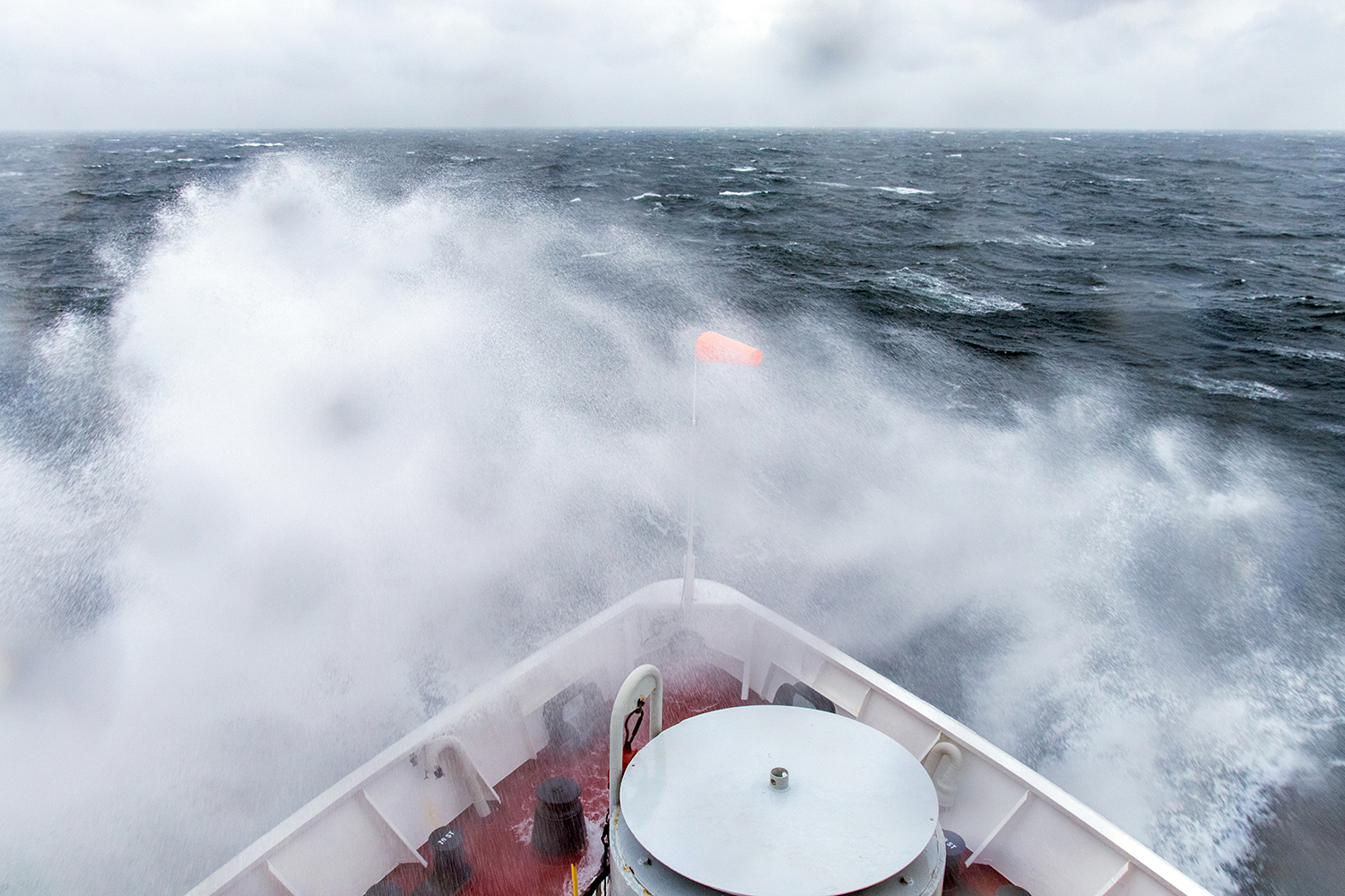 wave breaking over the bow of a ship on the ocean