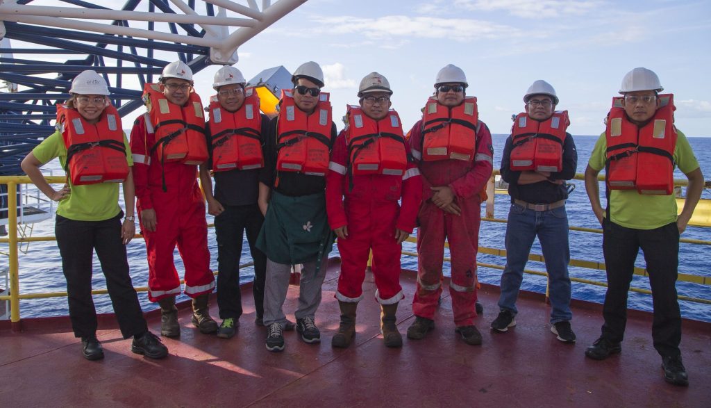 A line of people dressed in hard hats, safety glasses, and life jackets