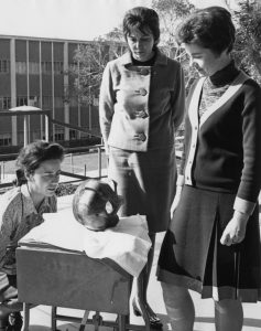 Three women looking at a scientific instrument while standing outdoors