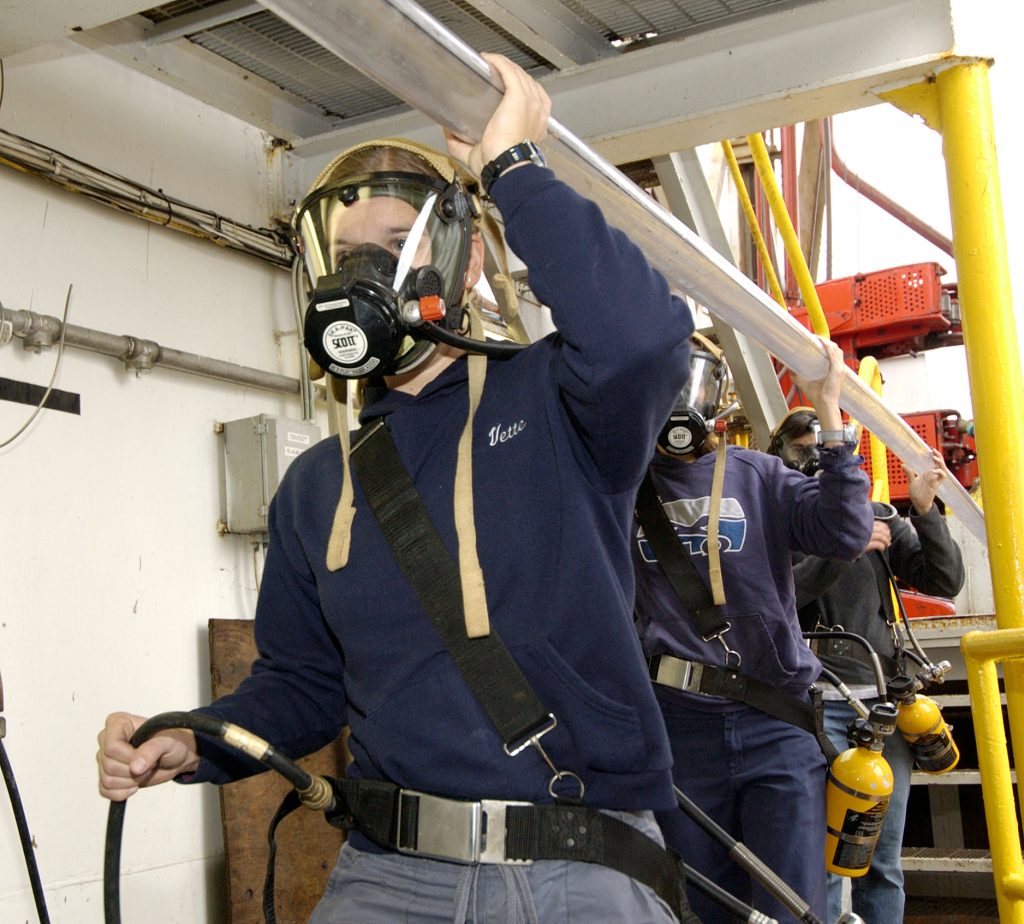 people wearing safety masks and hard hats while carrying an empty core liner over the left shoulder