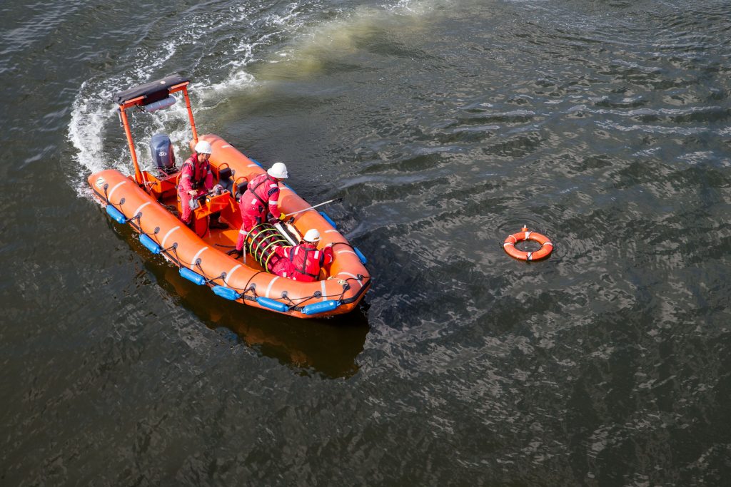 people in a small rescue boat practicing a rescue at sea with a life ring