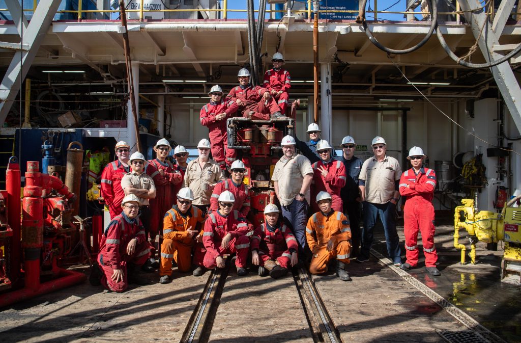 group of men wearing red coveralls and white hardhats on the deck of a ship