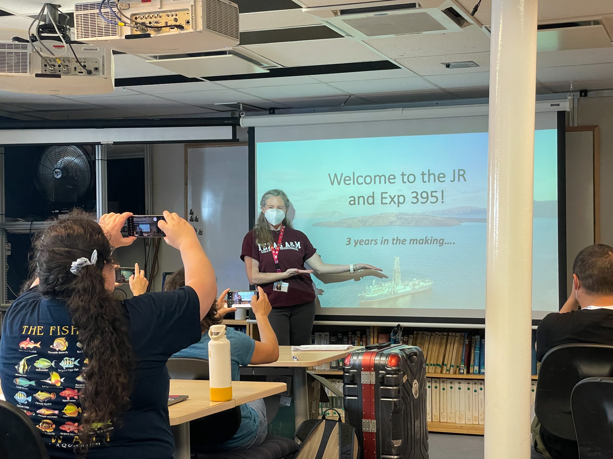 A women presenting to a room full of people about the upcoming expedition.