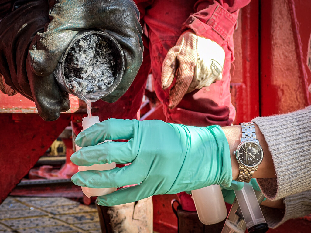 A geochemist takes a water sample directly from the core liner on the rig floor