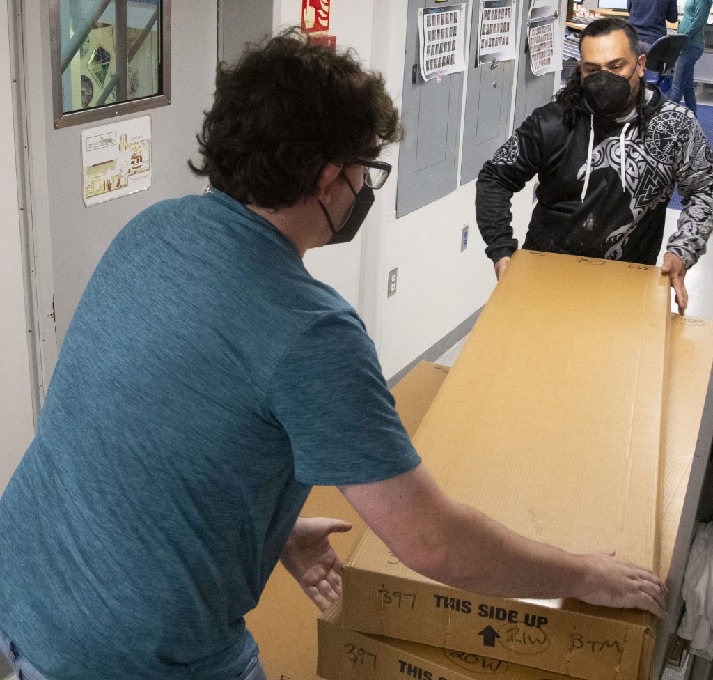 two people wearing masks working with rectangular boxes