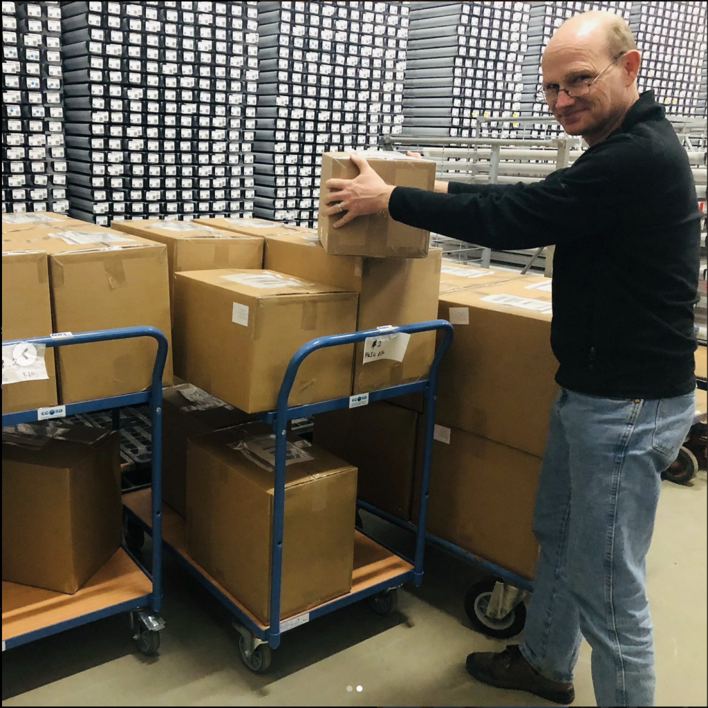 Person in front of three carts of boxes.