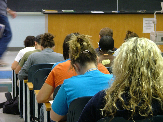 College students sitting in a lecture hall, taking an exam